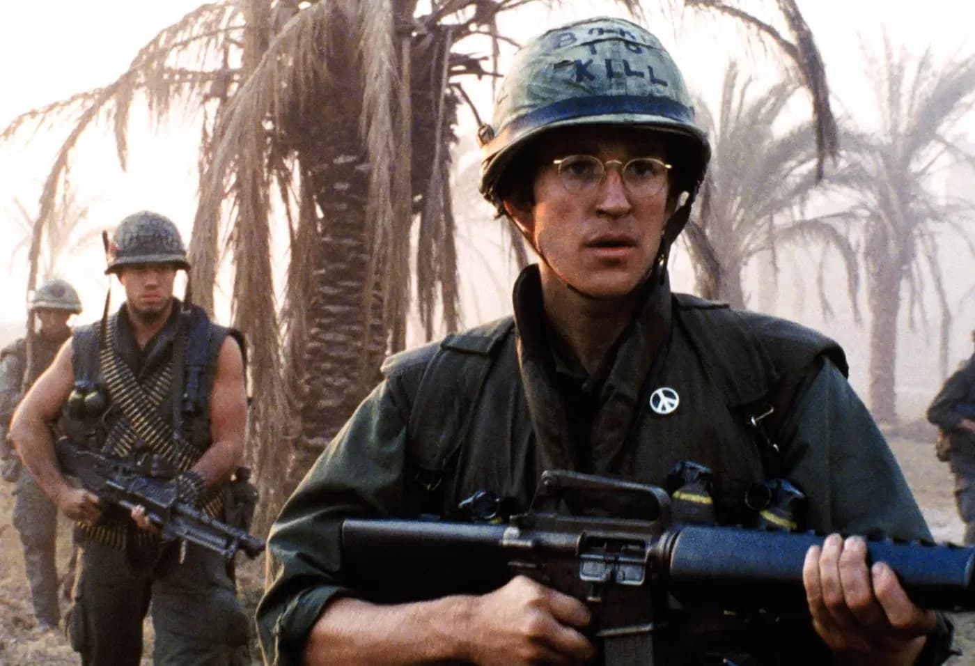 Private Joker (Matthew Modine) in Stanley Kubrick's Full Metal Jacket (1987), holding an M16 rifle with 'Born to Kill' written on his helmet and a peace symbol pin on his uniform jacket.