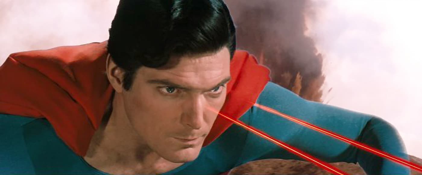 Close-up of Superman flying and using his heat vision with glowing red laser beams from his eyes.