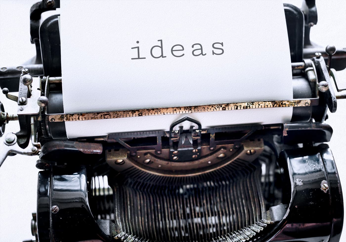 A close-up of a vintage typewriter with a white page inserted, the word 'ideas' typed on it